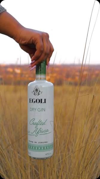 Egoli gin bottle held in an outdoor grassland setting